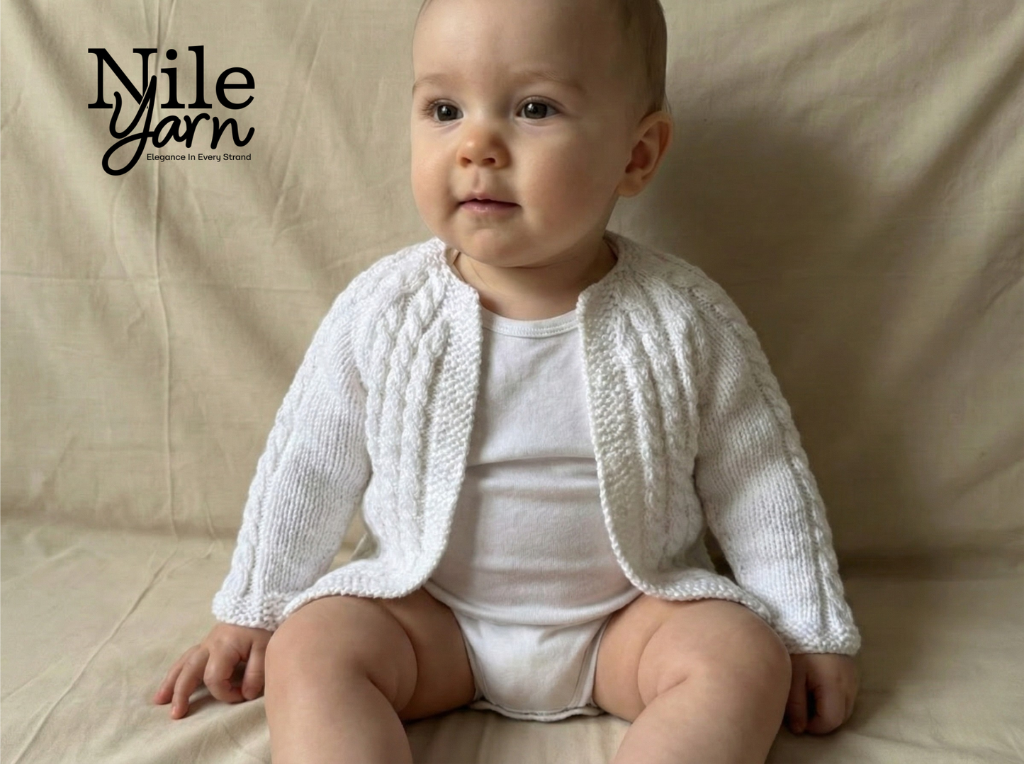 Baby wearing a white knitted cardigan sitting on a beige surface with 'Nile Yarn' branding.