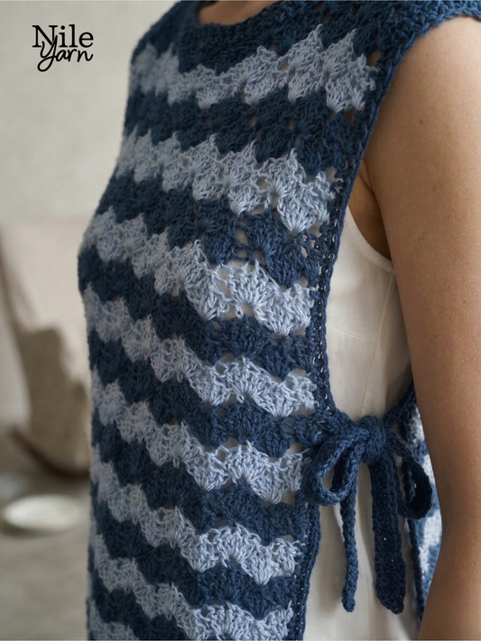 Close-up of a crocheted side-tie closure on a blue wave-stitch top, showing the texture of the Neith Nile Yarn and the adjustable side-tie detail